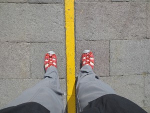 Feet straddling a yellow line supposed to mark the equator