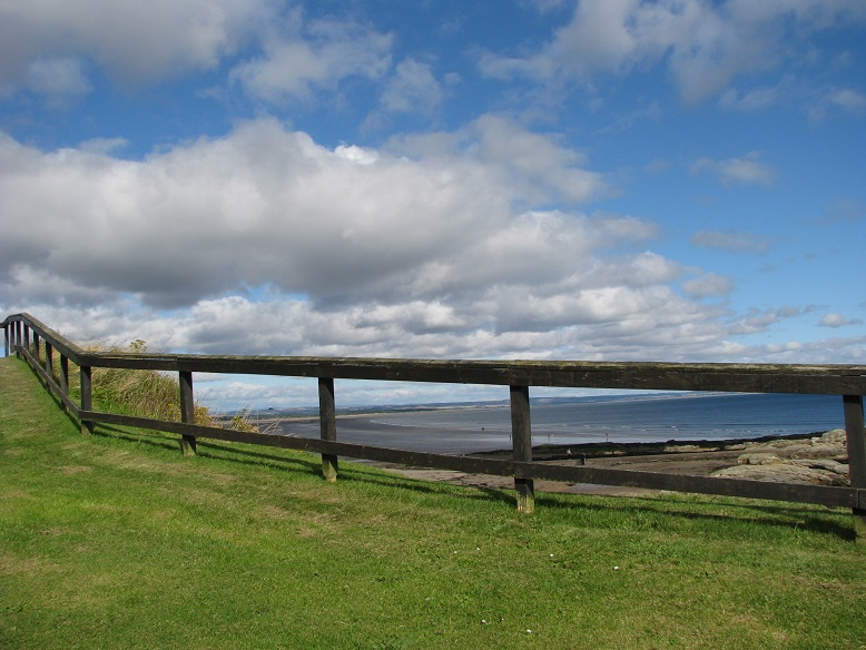 View through wooden fence of beach at St. Andrews, Scotland, from cliff above.