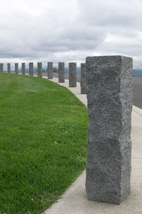 Series of rectangular, grey granite bollards curving back to left.