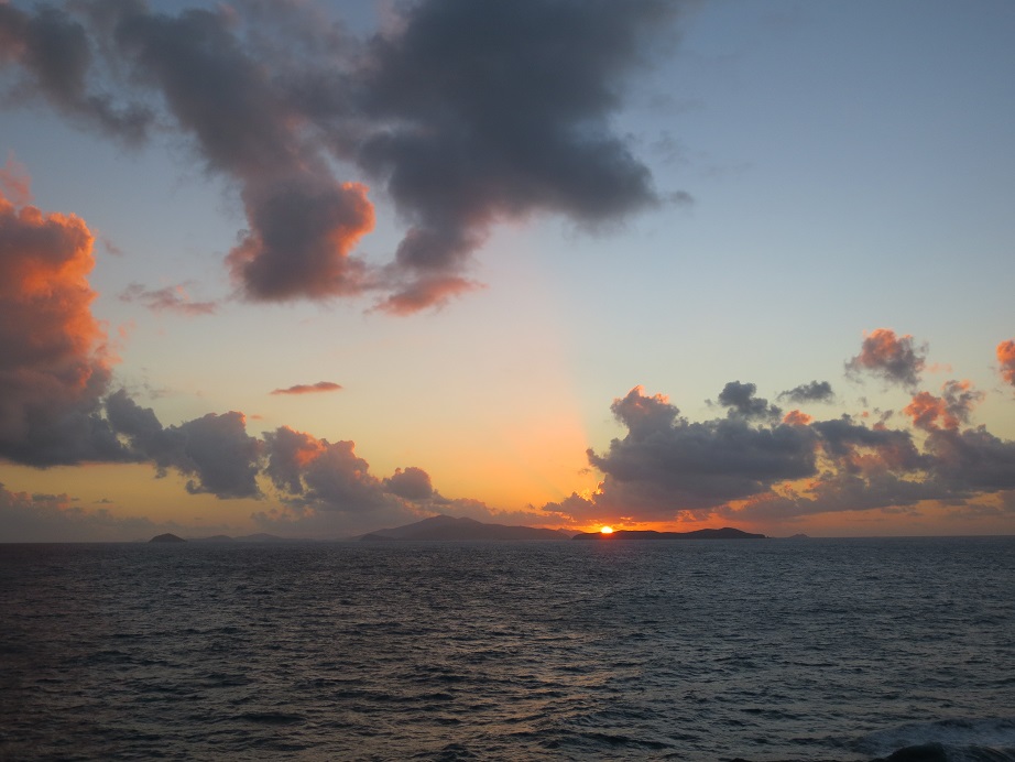 Sunrise over St. Thomas, with islands in silhouette beneath a pale blue sky.
