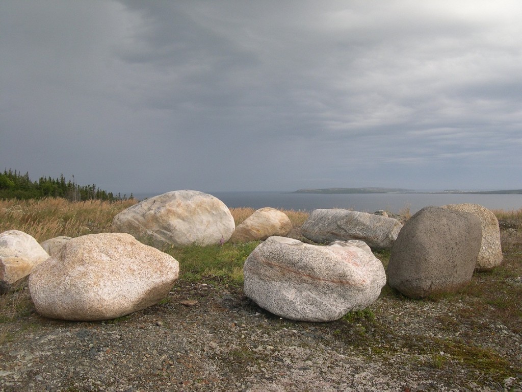 Close-up of rocks on a hillside overlooking sea in the background.