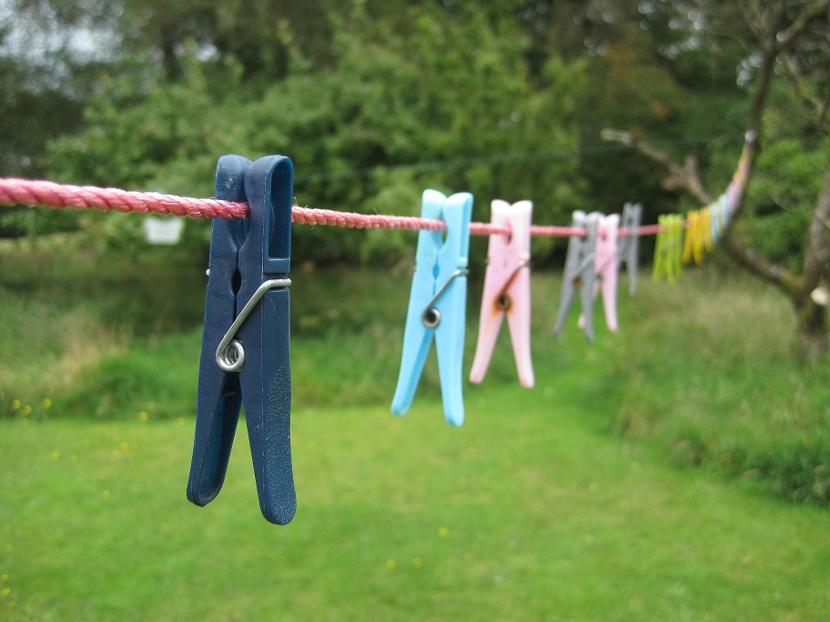 Multi-coloured plastic clothespins stretching along a red clothesline.