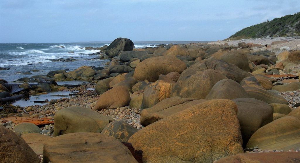 Sideways view of rocky beach at ground level; ocean on left, shore on right.