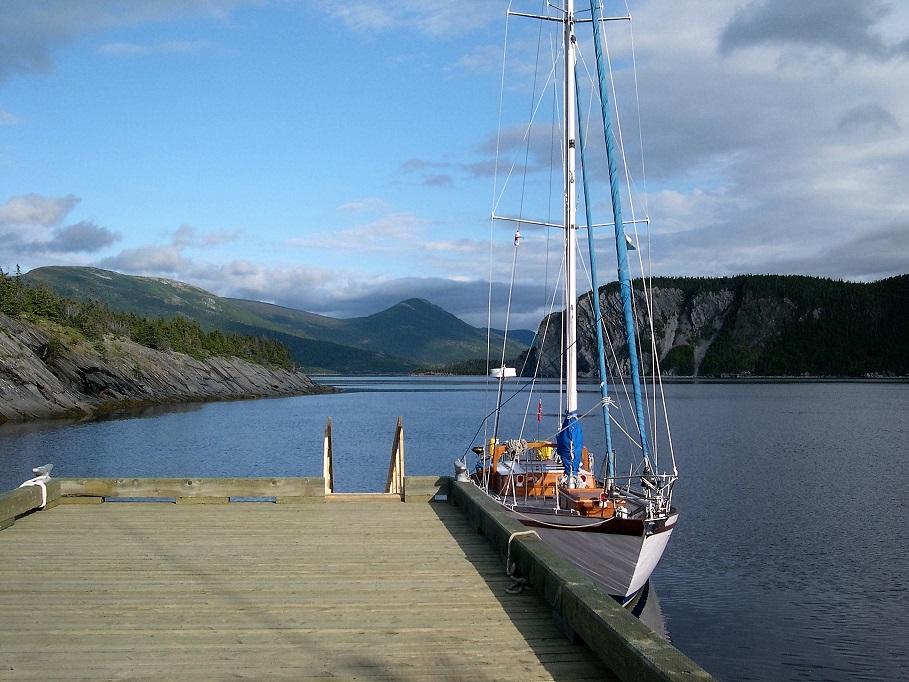 Sailboat alongside dock; mountains in background.