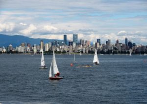 View of city across water; sailboats in foreground