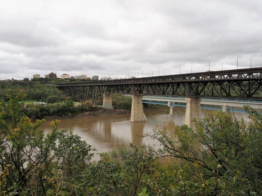 Trestle rail bridge across muddy North Saskatchewan River.