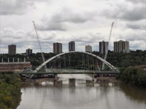 Three-truss bridge with replacement two-arch bridge soaring above it.