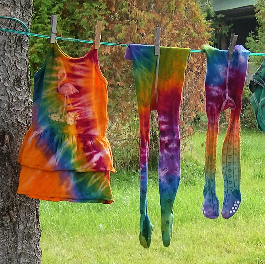 Tie-dyed clothes hanging on a clothesline.