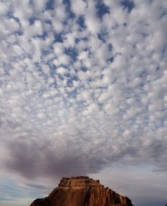 Golden mountain topped by fluffy clouds over Lake Powell.