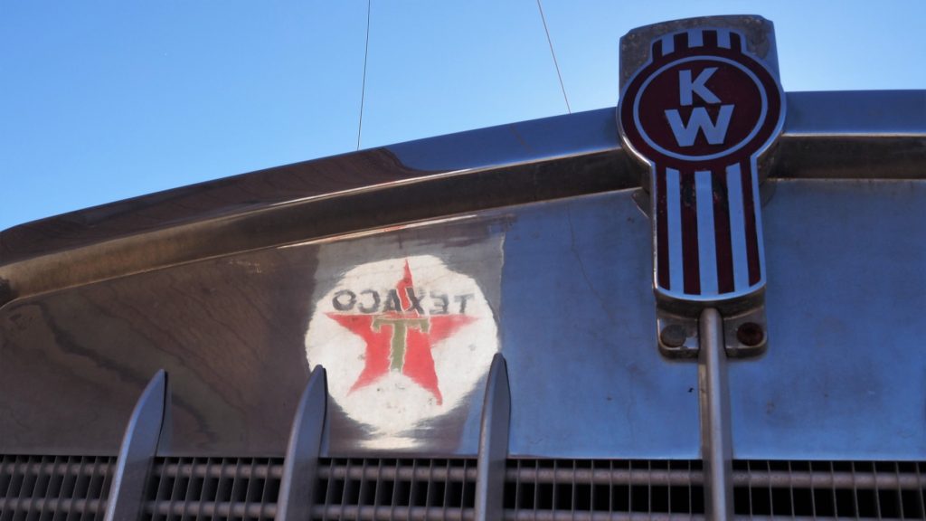 Texaco sign reflected in hood of semi-truck cab.