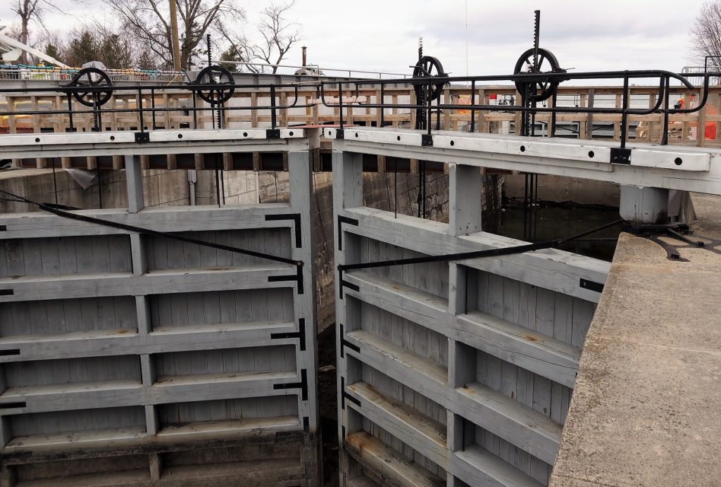 Grey wooden gates of dry lock, partially open.