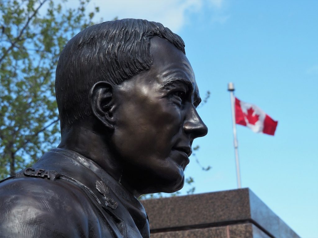 Bust of John McCrae with Canadian flag in background.