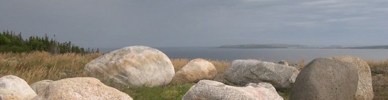 Close-up of rocks on a hillside overlooking sea in the background.