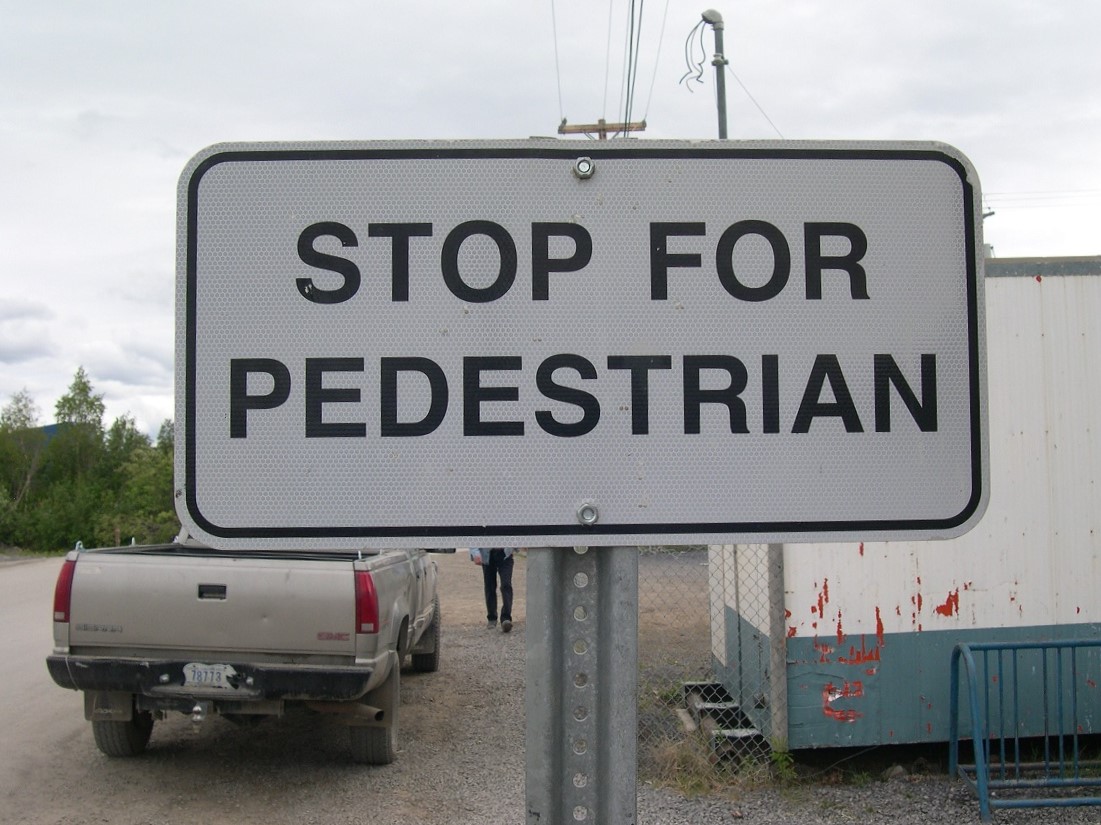 Black and white traffic sign: Stop for Pedestrian (singular)