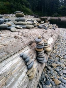Smmoth stones piled on driftwood log on beach