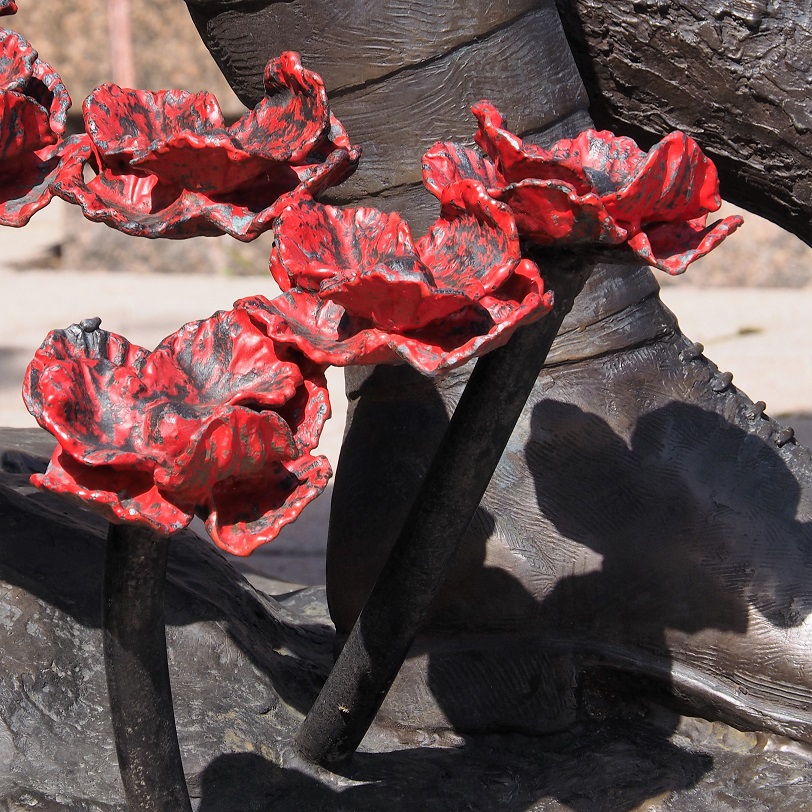 Detail of poppies on memorial statue.