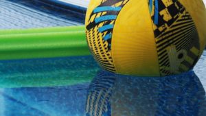 Close-up of ball and noodle and their reflections in the pool.