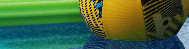 Close-up of ball and noodle and their reflections in the pool.