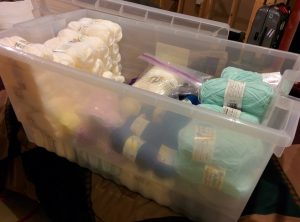 Translucent tub of ~75 skeins of baby yarn