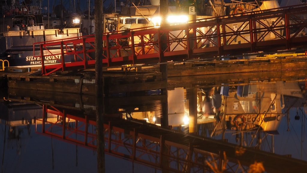 Fishing boat reflected in water at night.