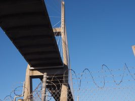 Vie of bridge from street level, with razor wire in foreground.