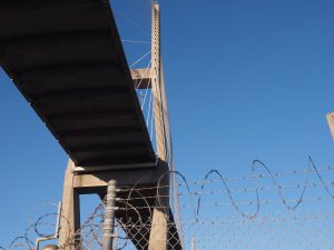 Vie of bridge from street level, with razor wire in foreground.