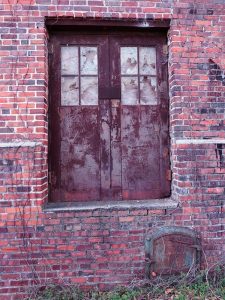 Old doors with broken window panes in abandoned warehouse