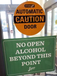 Grocery-store door sign advising patrons that they can't take open alcohol out into the parking lot