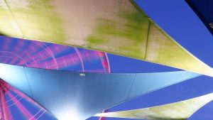 Moving Skywheel peeking through coloured, wing-shaped canvas awnings
