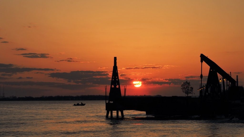 Orange-red sunrise over Detroit River with equiipment silhouetted in foreground.