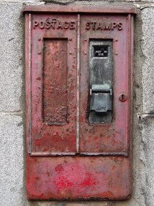 Sign proclaiming "Not in use" on decrepit postage-stamp dispenser.