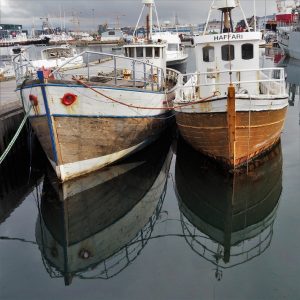 White and brown fishing boats and reflection.